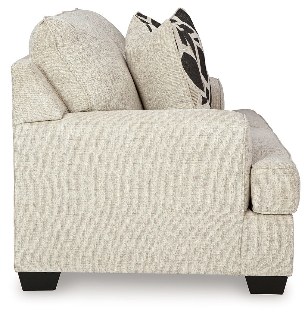 Light beige loveseat side view with rolled arms and two geometric black-and-beige pillows