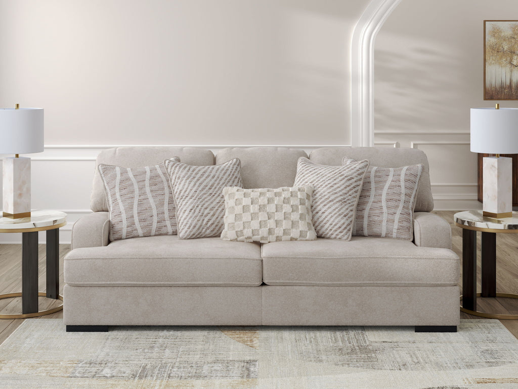 Taupe upholstered sofa with four patterned throw pillows, striped and checkered cushions