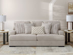 Taupe upholstered sofa with four patterned throw pillows, striped and checkered cushions