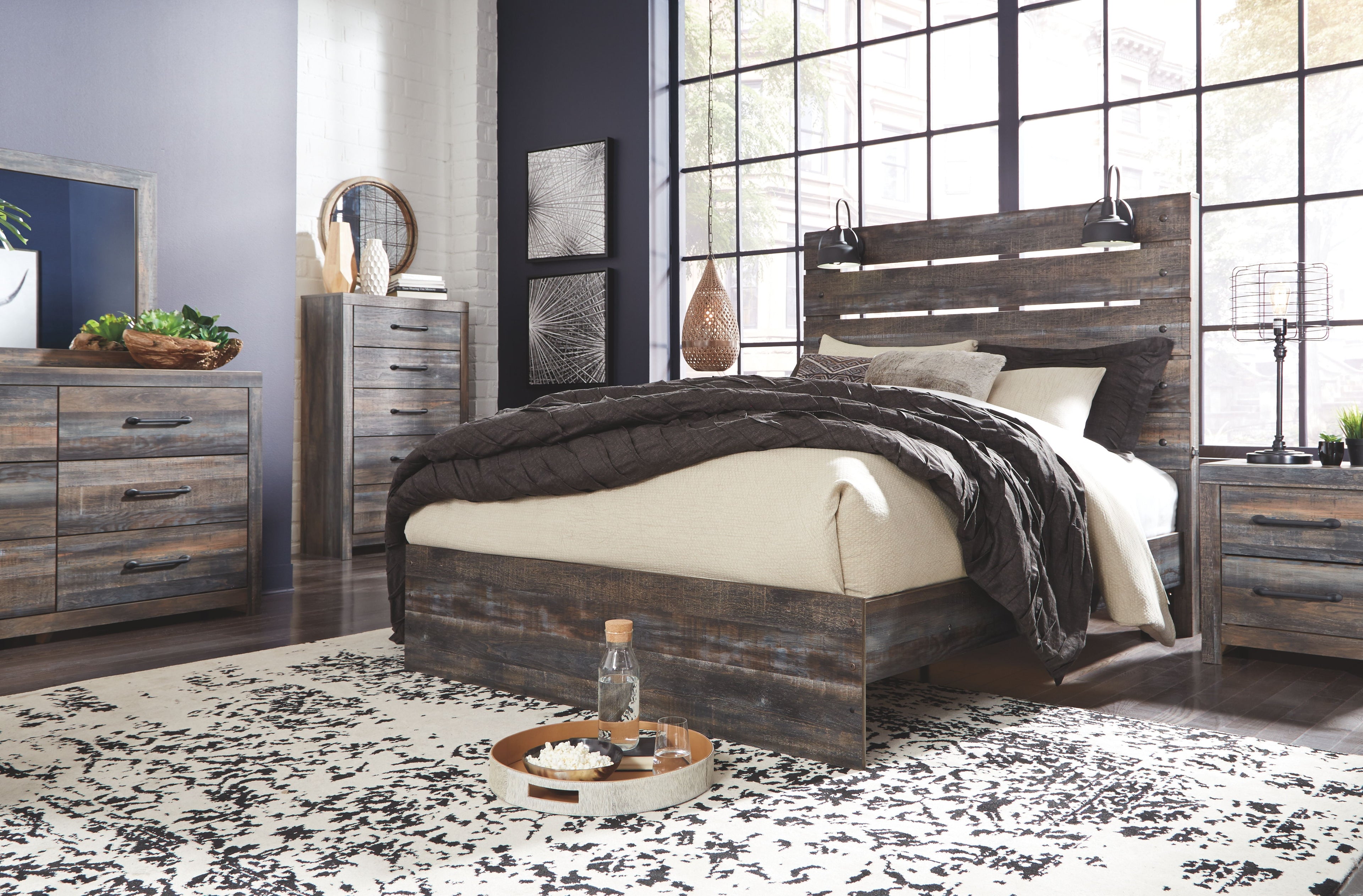 Rustic wood dresser with six drawers and black bar pulls, placed beside a bed