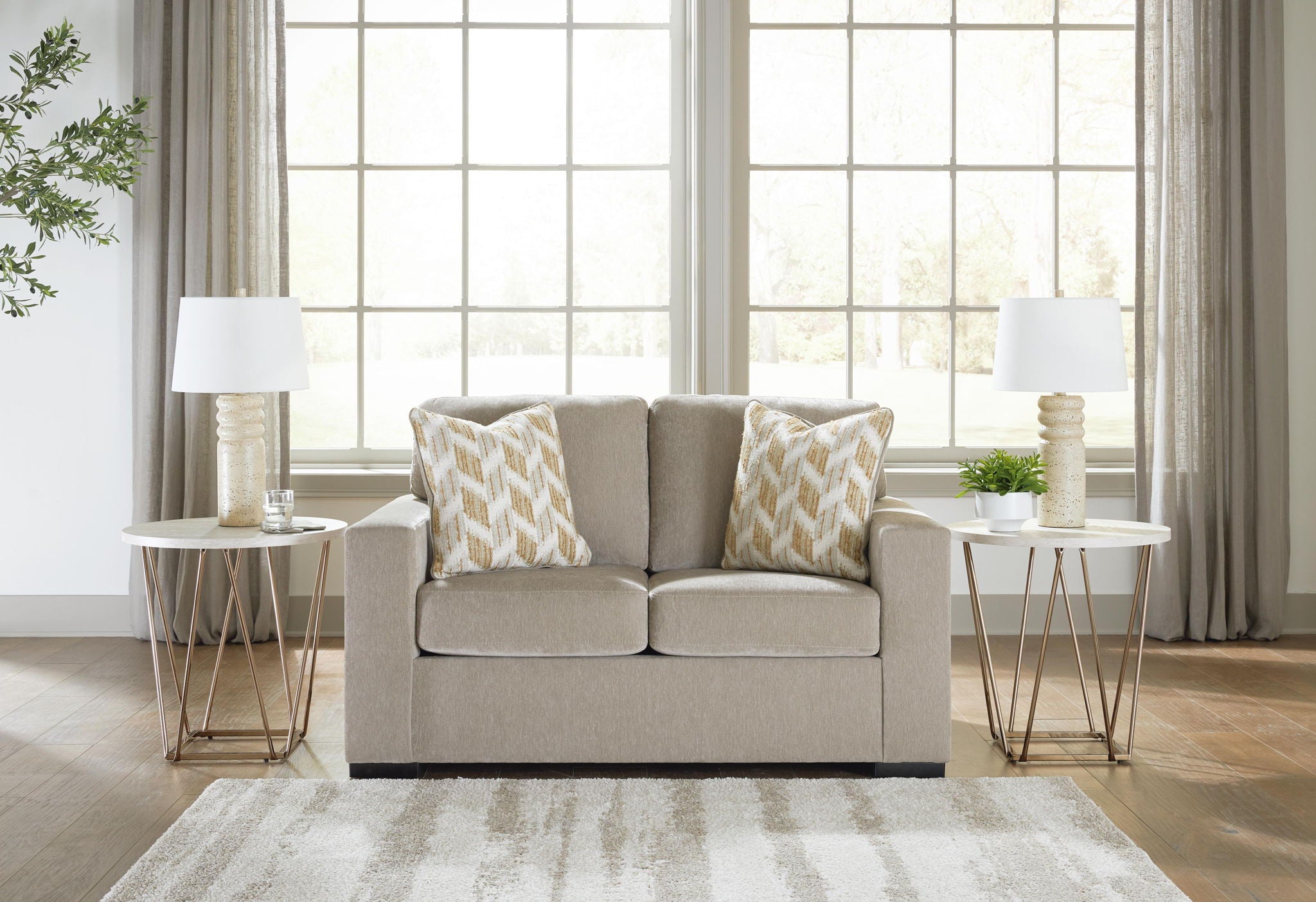Gray upholstered loveseat with two patterned accent pillows and square arms