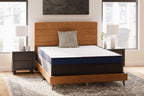 Firm mattress with white top and dark blue sides on a dark wood bed frame