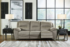 Reclining sofa in light putty gray upholstery with padded arms and plush seat cushions