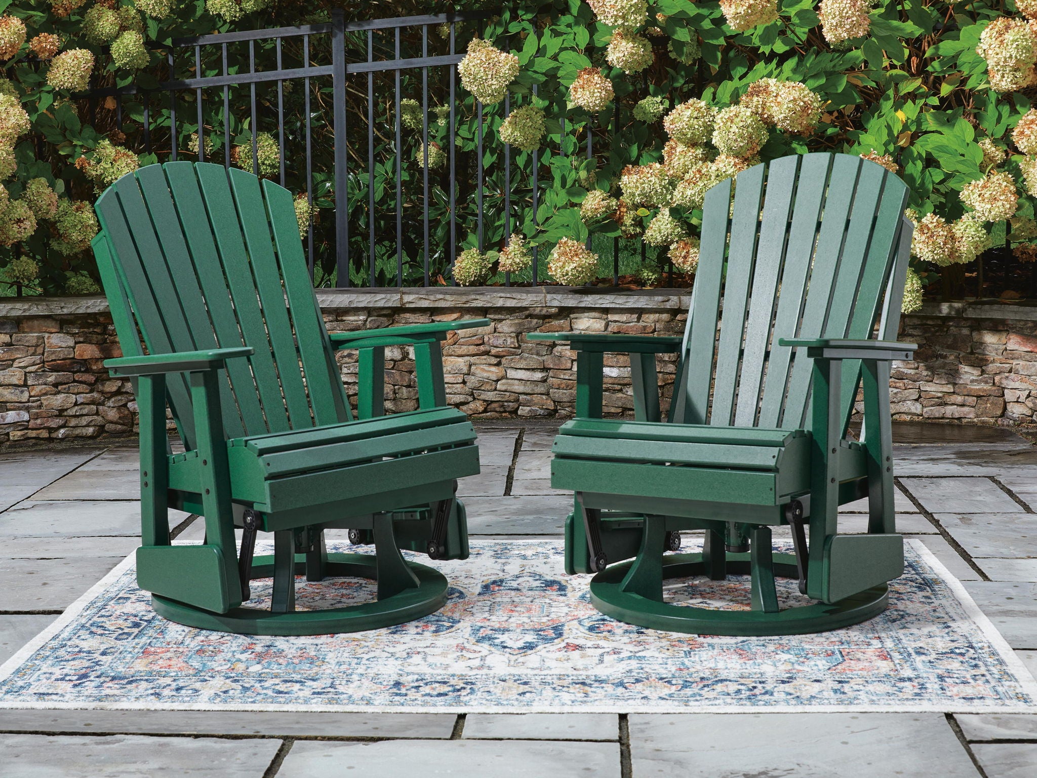 Pair of green swivel glider rocking chairs with slatted backs and seat boards