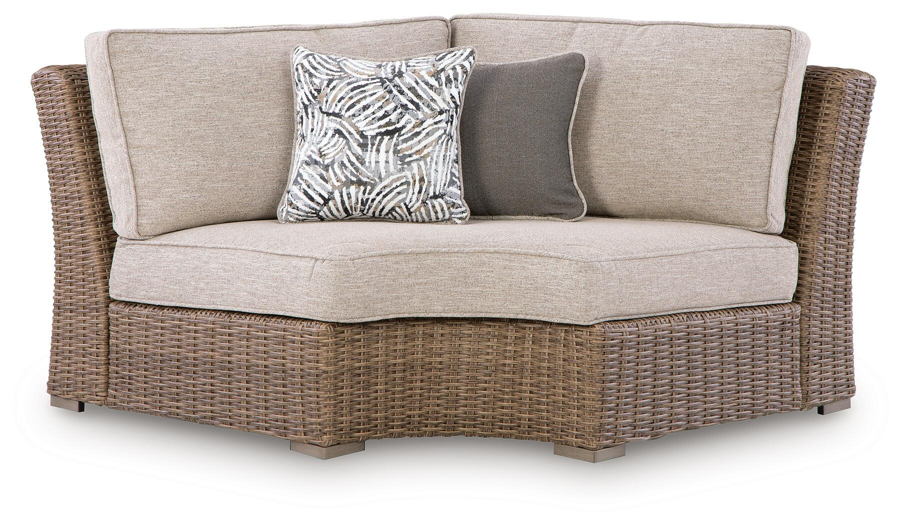 Beige curved corner chair with seat cushion, woven wicker base, zebra accent pillow