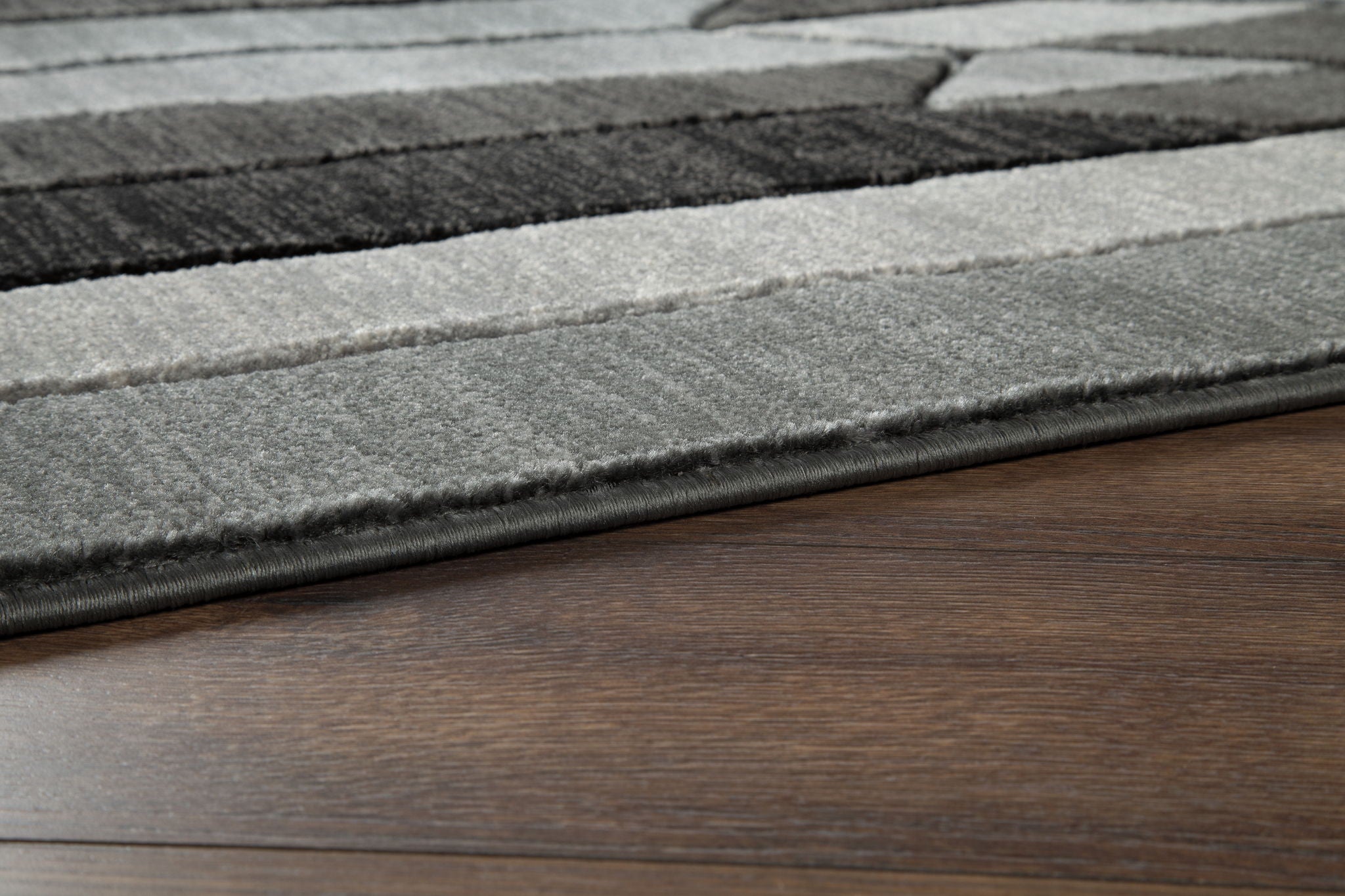 Dark gray and light gray geometric area rug edge with flat woven border