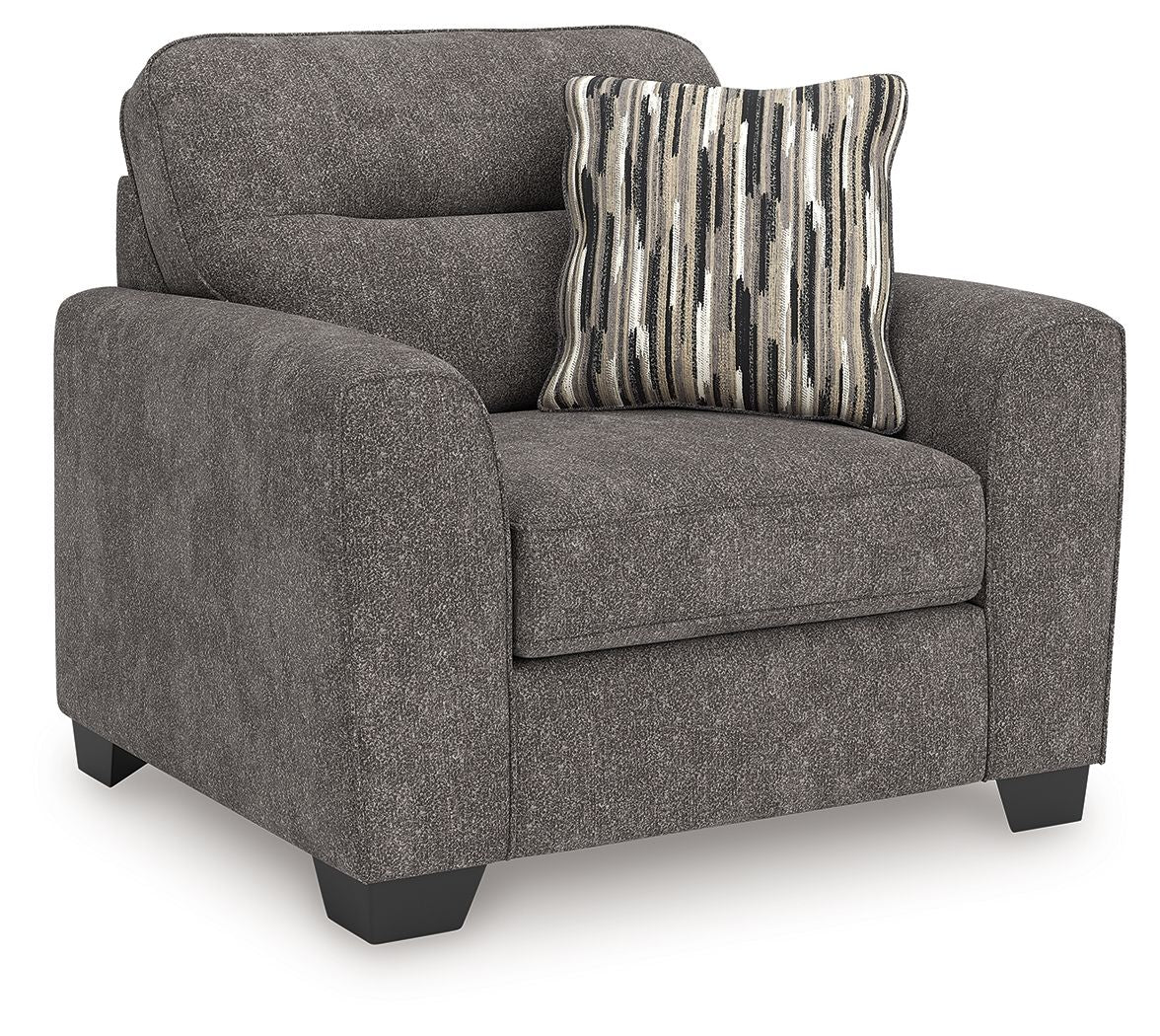 Dark gray upholstered chair and a half with rounded arms and striped throw pillow