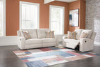 Beige reclining sofa and loveseat set with patterned throw pillows and recliner open