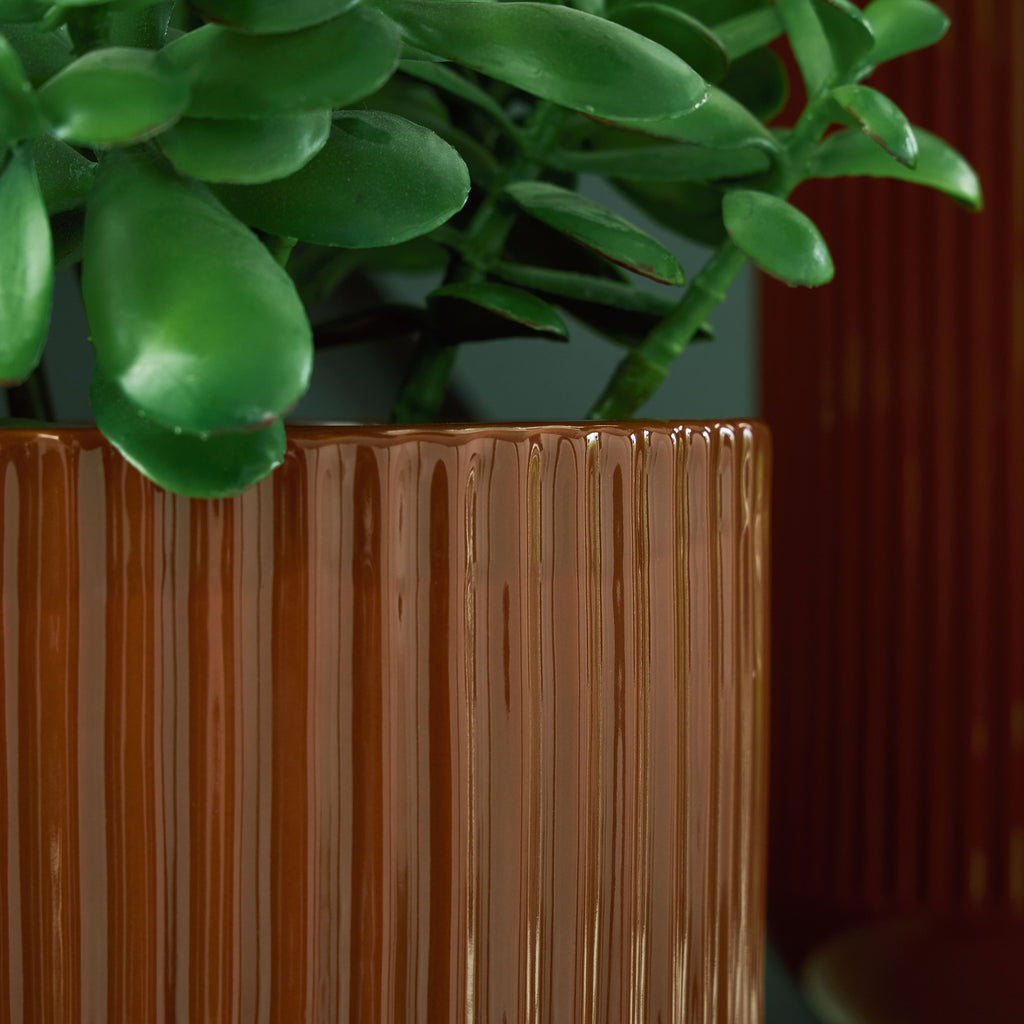 Small dark brown fluted vase rim with vertical ridges, partially filled with stems
