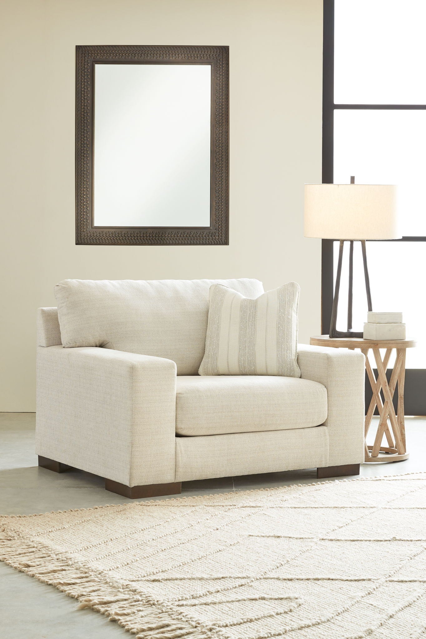Light beige living room chair with two striped throw pillows and ottoman