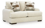 Light cream loveseat sofa with two seat cushions, square arms, dark legs, patterned pillows
