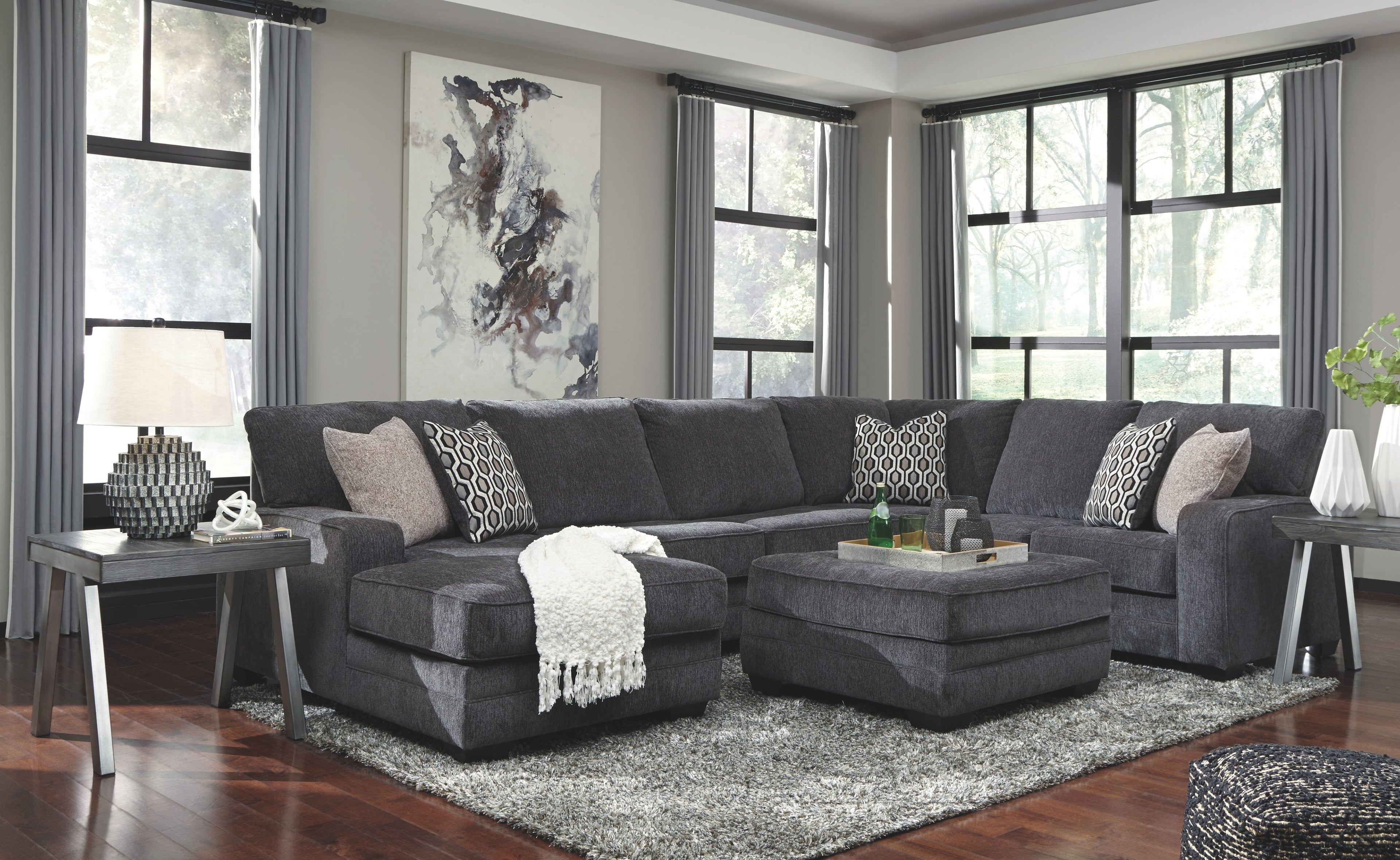 Dark gray sectional sofa with chaise and accent ottoman, patterned throw pillows