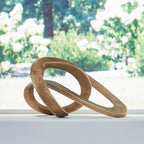 Antique brass metal sculpture with curved interlocking loops, abstract oval form