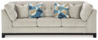 Stone fabric sofa with tufted arms and two decorative geometric throw pillows