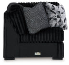 Black wedge sofa with ribbed texture, gray throw cushion and geometric pillow