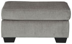 Light gray upholstered ottoman with cushioned top and squared sides