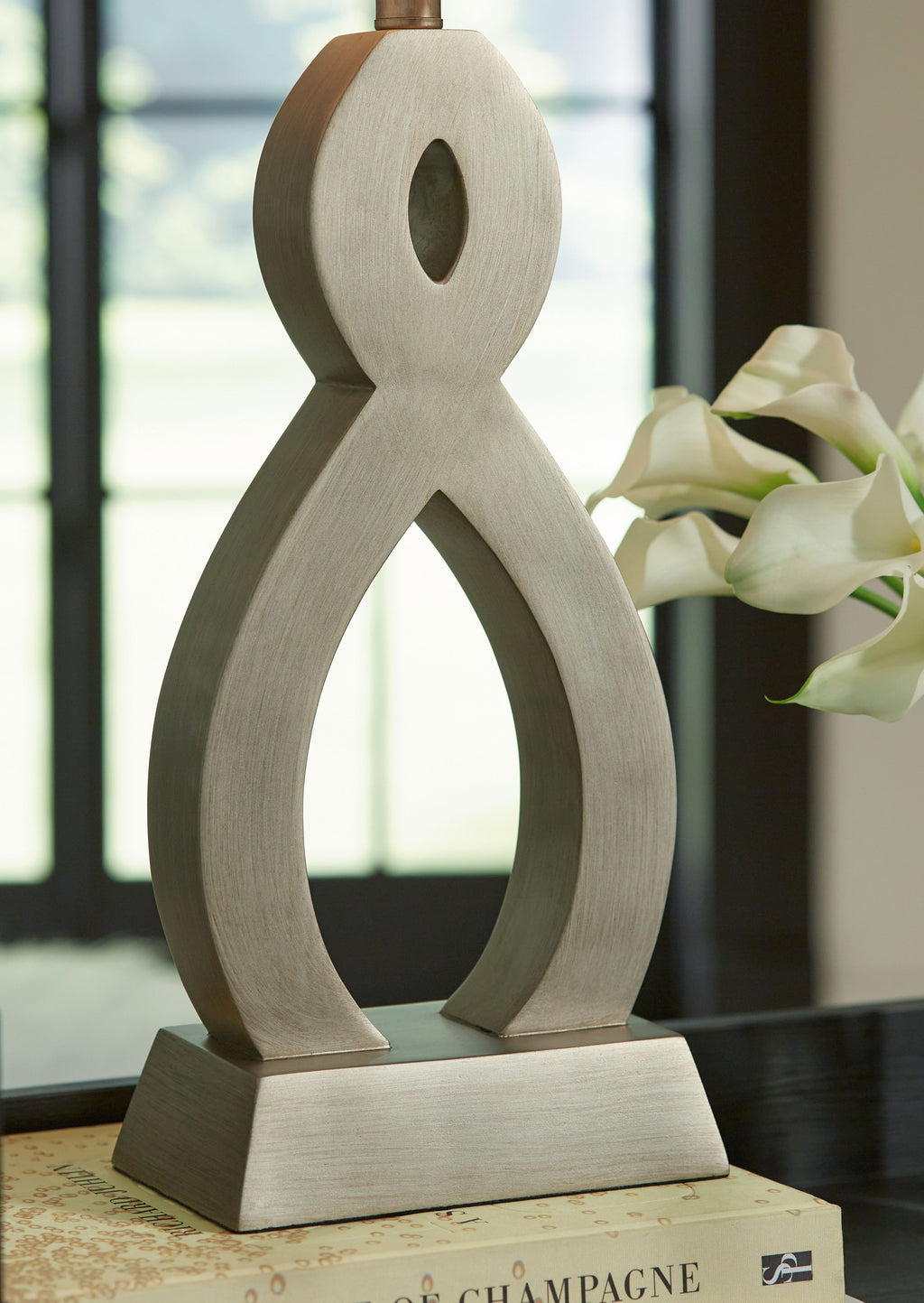 Table lamp with off-white drum shade and oval cutout sculpted gray base