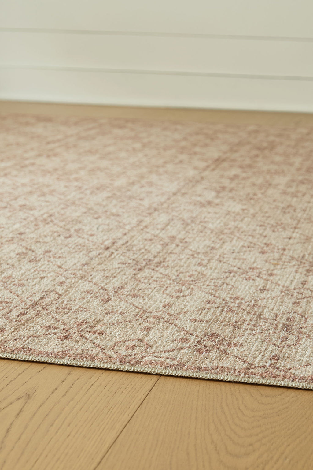 Textured area rug with short beige pile and faint red geometric speckles