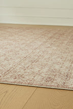 Textured area rug with short beige pile and faint red geometric speckles