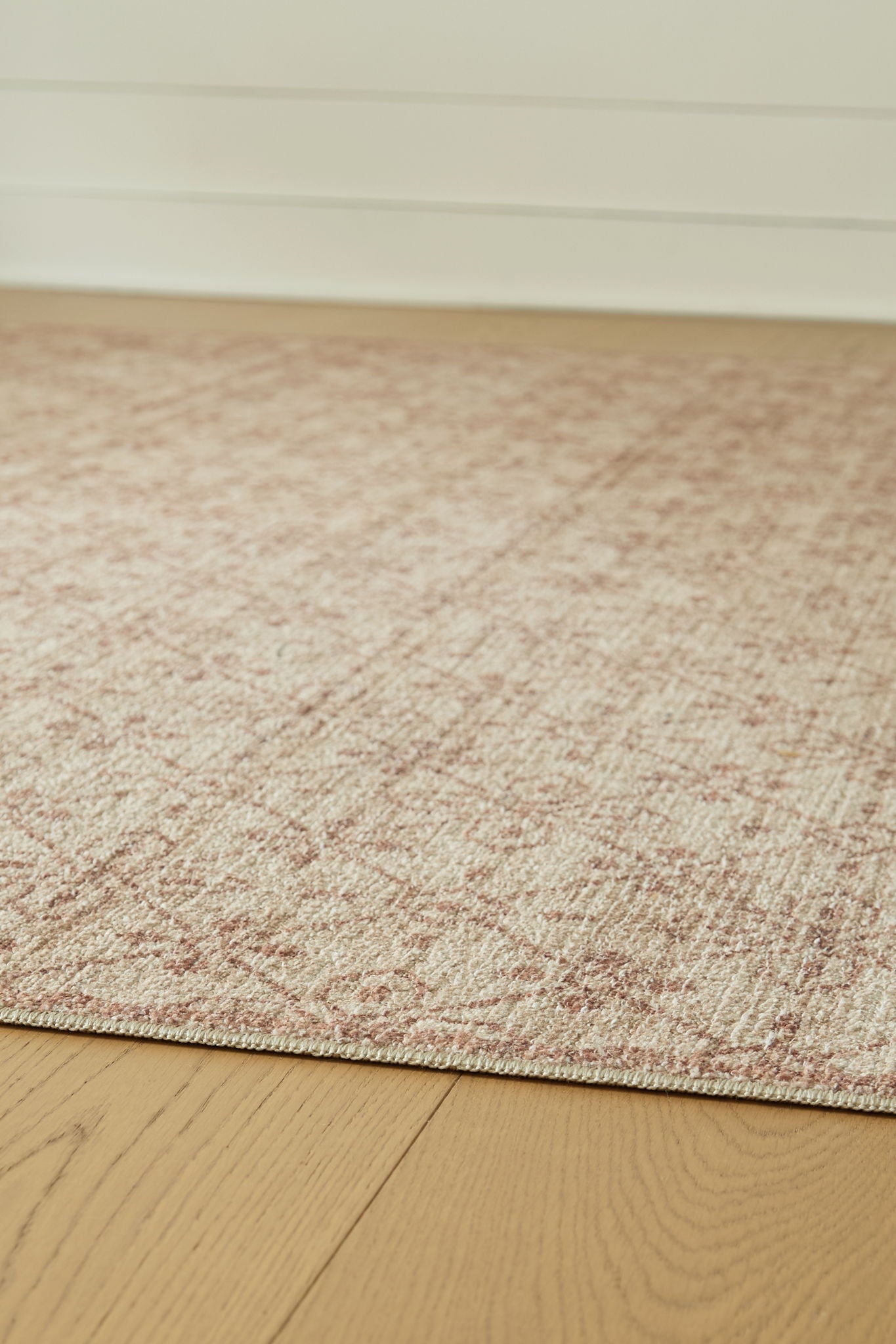 Textured area rug with short beige pile and faint red geometric speckles