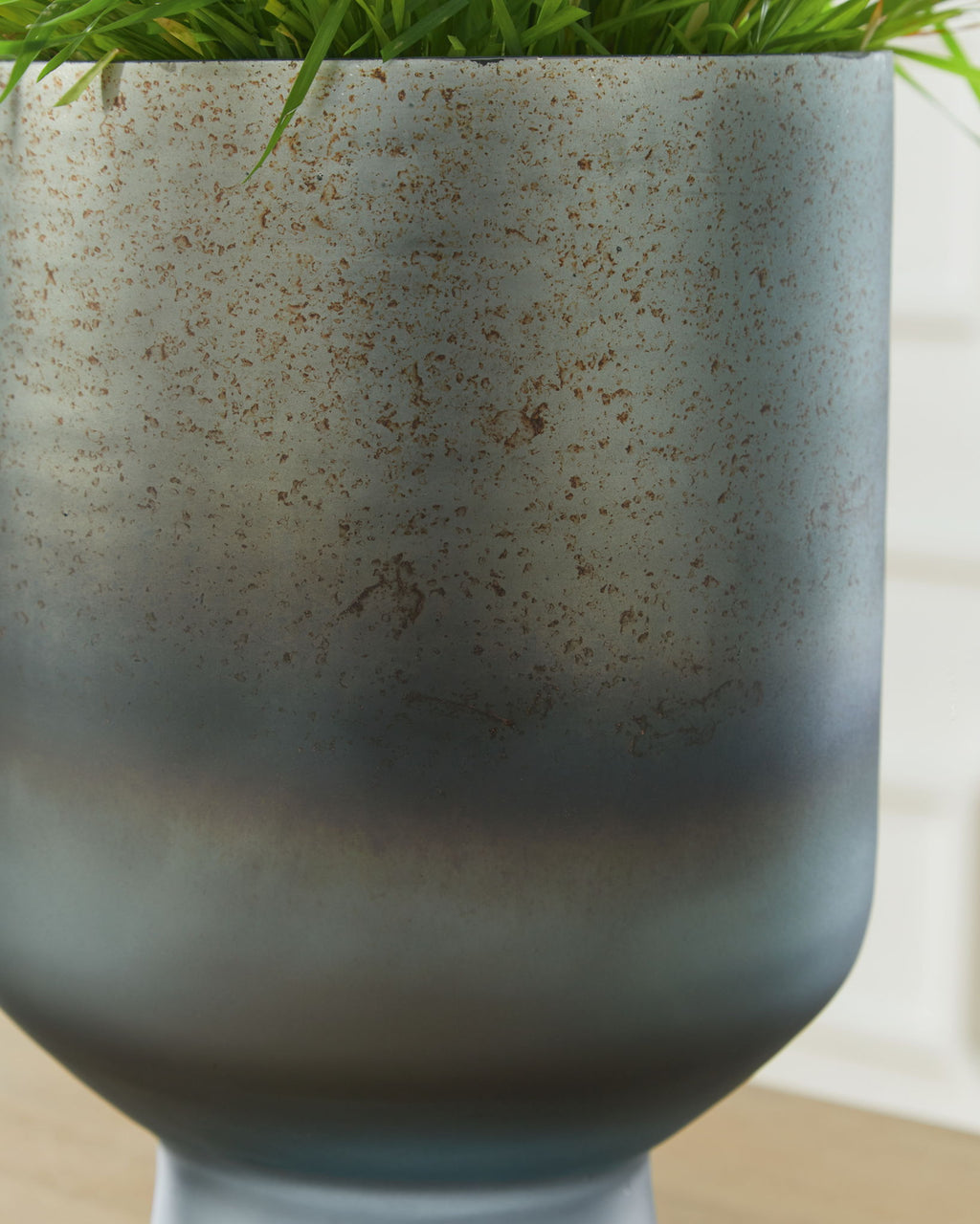 Blue speckled vase with flared rim, close-up view of curved body.