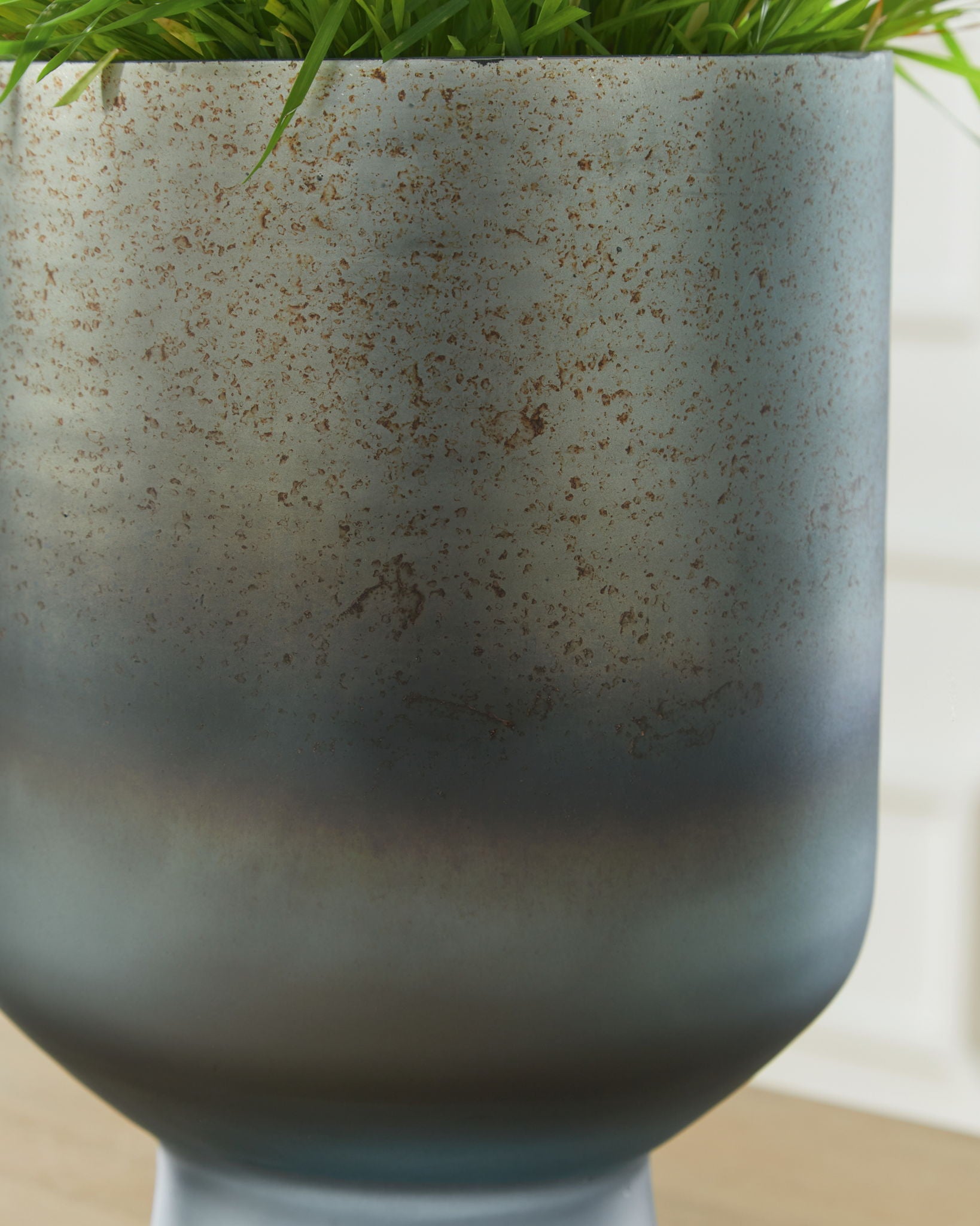 Blue speckled vase with flared rim, close-up view of curved body.