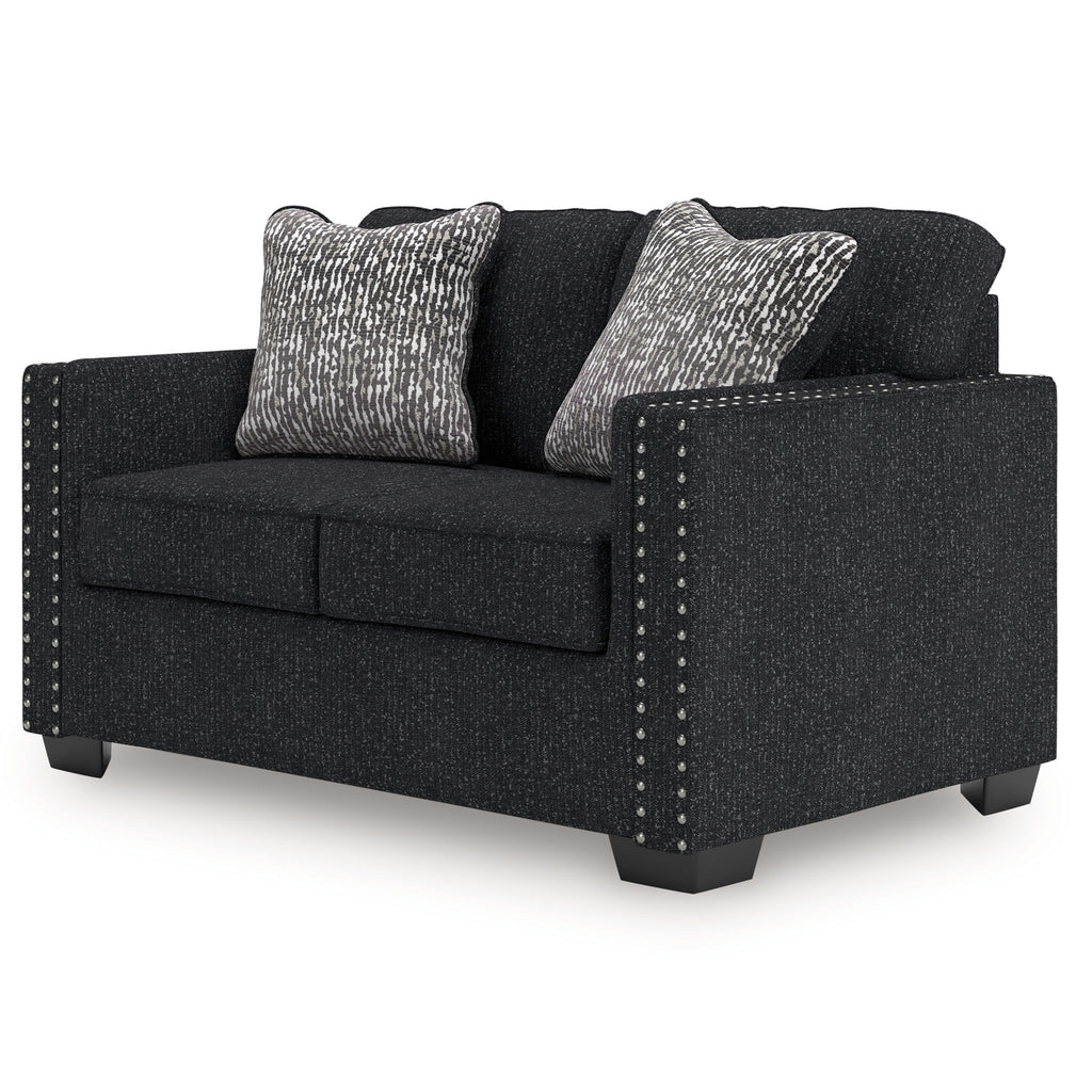 Charcoal loveseat with two patterned pillows and nailhead studded arm panels