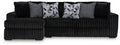 Black sectional sofa with chaise, ribbed upholstery, and patterned throw pillows