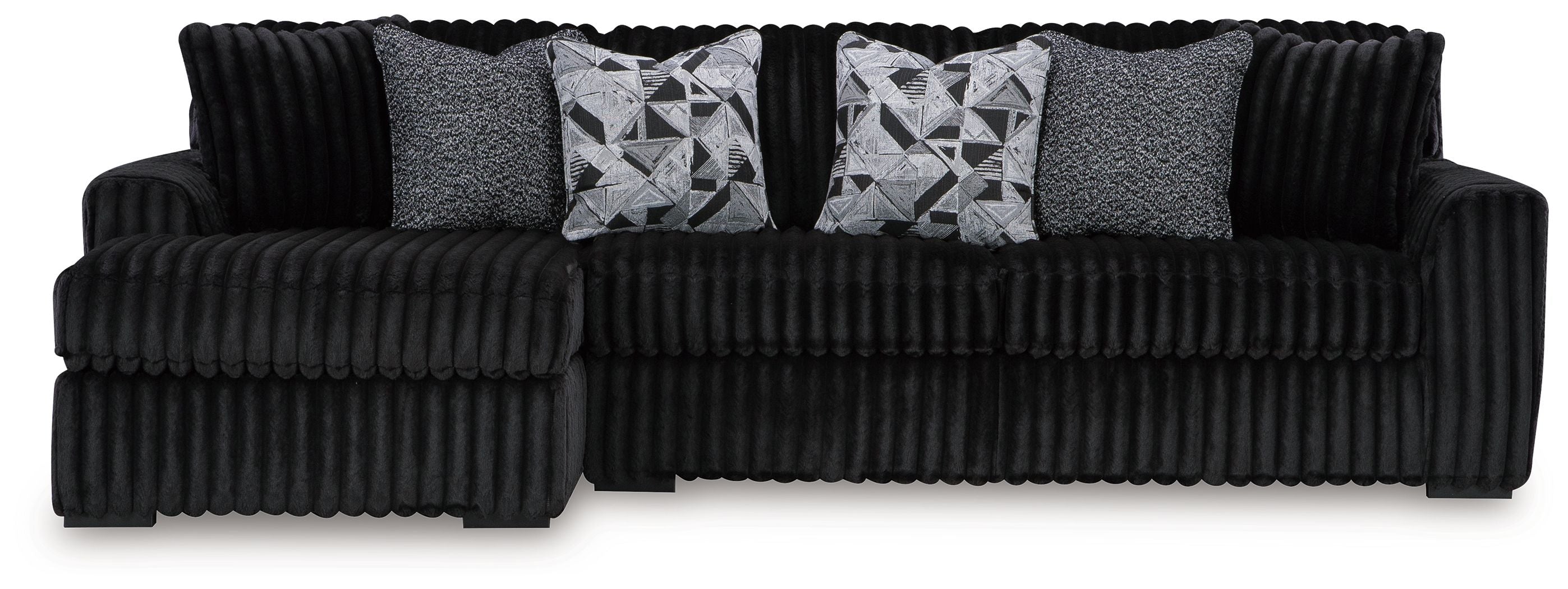 Black sectional sofa with chaise, ribbed upholstery, and patterned throw pillows