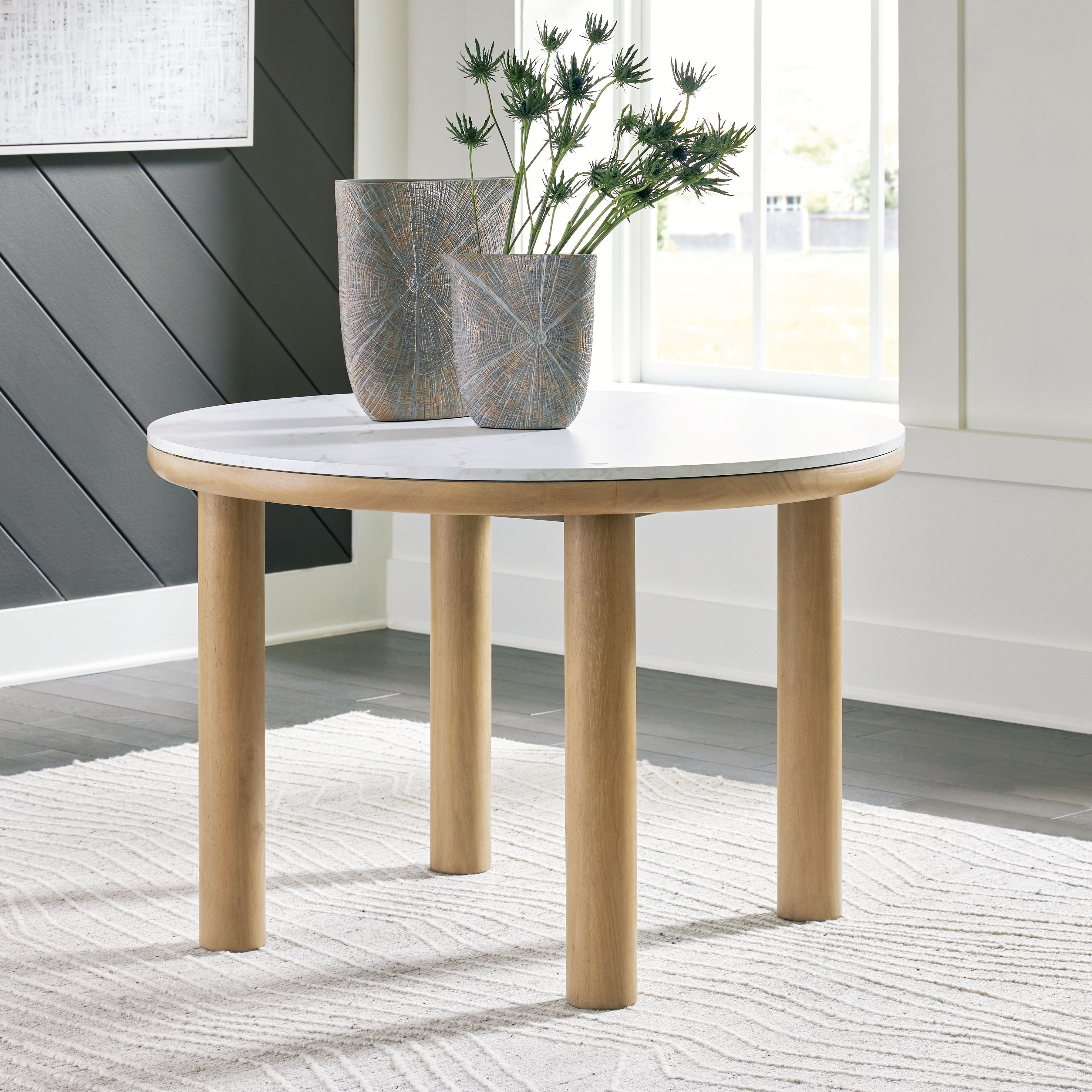 Round dining table with light gray marble-look top and light brown tapered legs