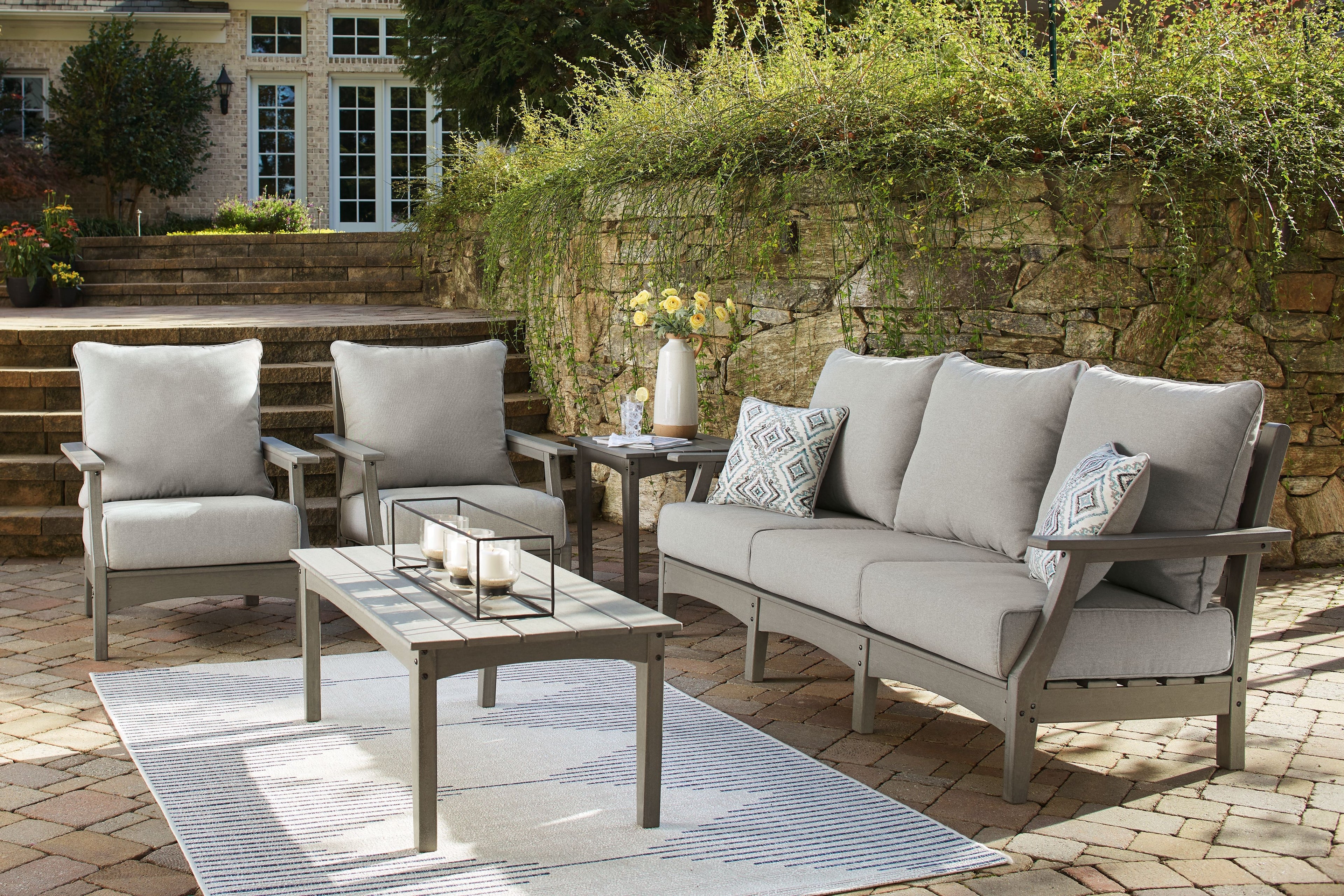 Gray outdoor lounge set with loveseat, two chairs, and coffee table; accent pillows