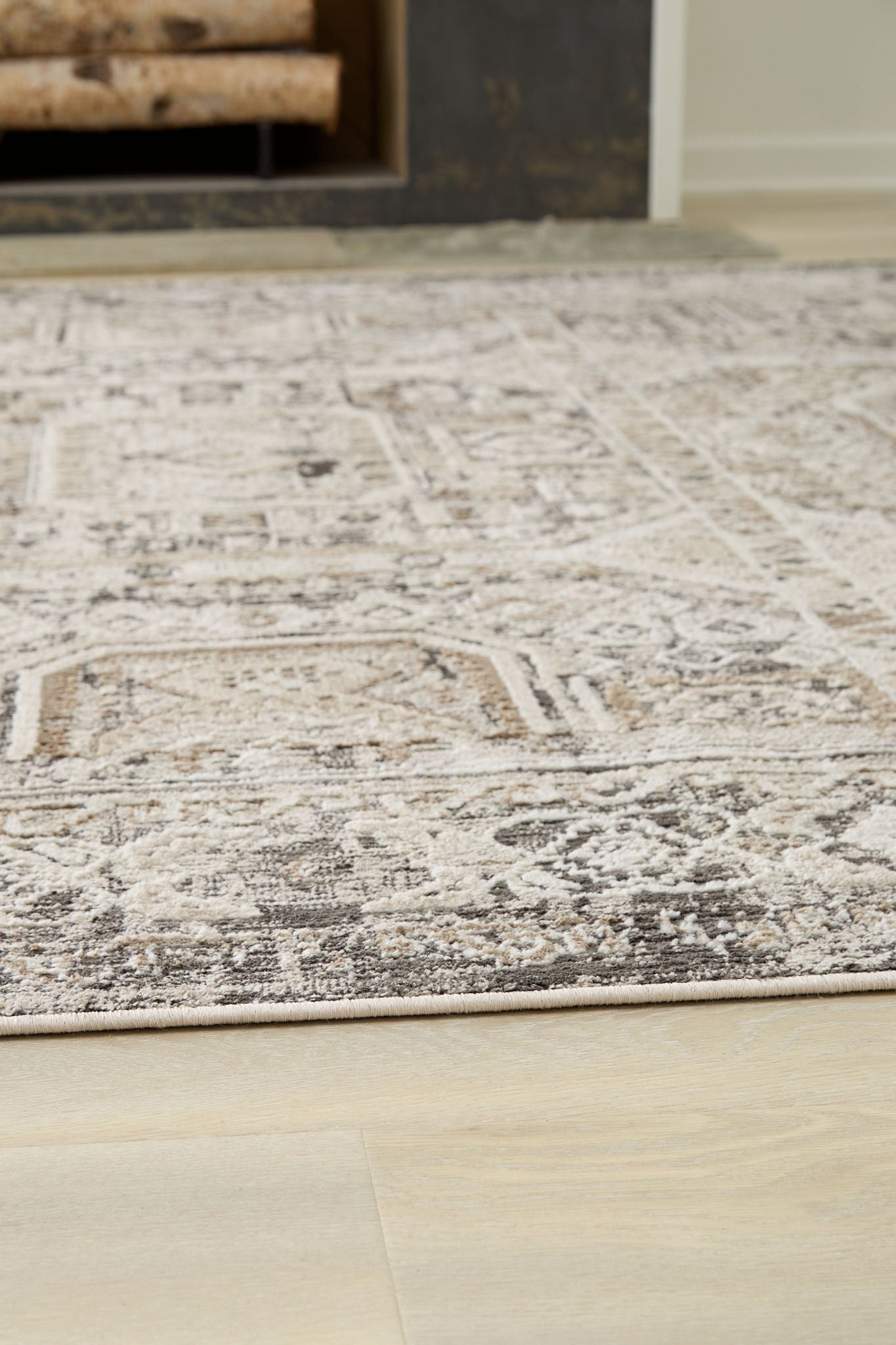 Distressed geometric rug with light off-white base and gray pattern on hardwood floor