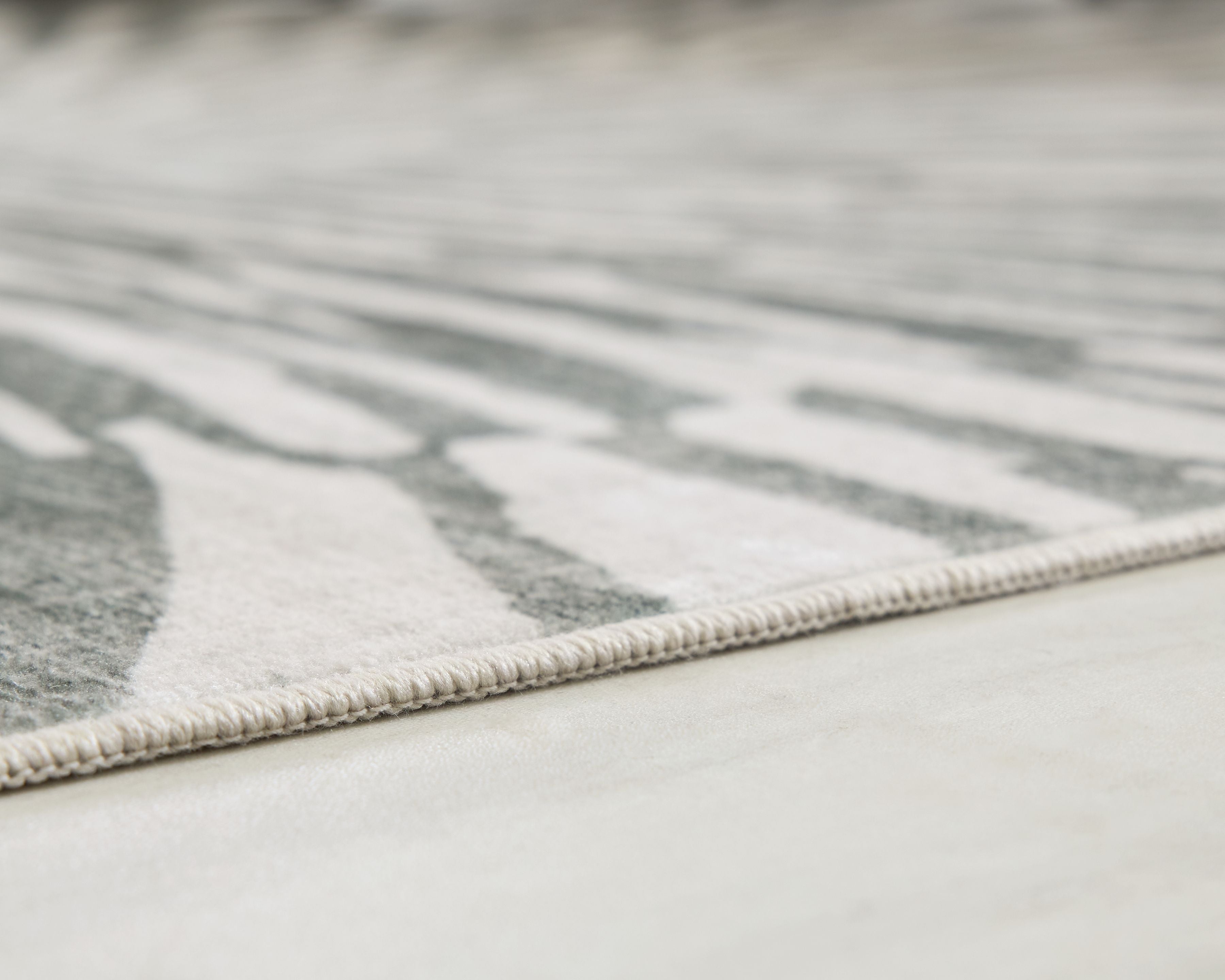 Gray and ivory washable rug with low-cut edge and subtle striped pattern near border