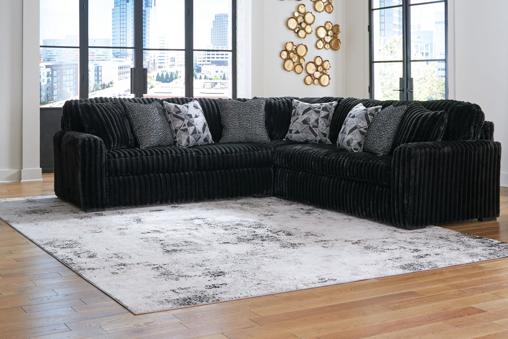 Black sectional sofa with chaise and patterned throw pillows, ribbed seat cushions