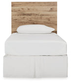 Beige wood panel headboard with arched top, behind white bed linens