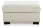 Cream upholstered ottoman with padded lid and ribbed sides, supported by dark legs