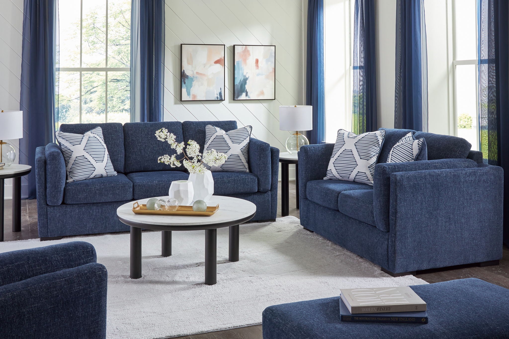 Blue living room sofa set with multiple patterned pillows and a matching armchair