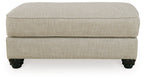 Fog beige ottoman with cushioned top, clean sides, and dark turned legs
