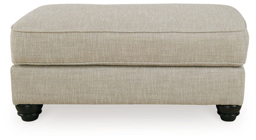 Fog beige ottoman with cushioned top, clean sides, and dark turned legs