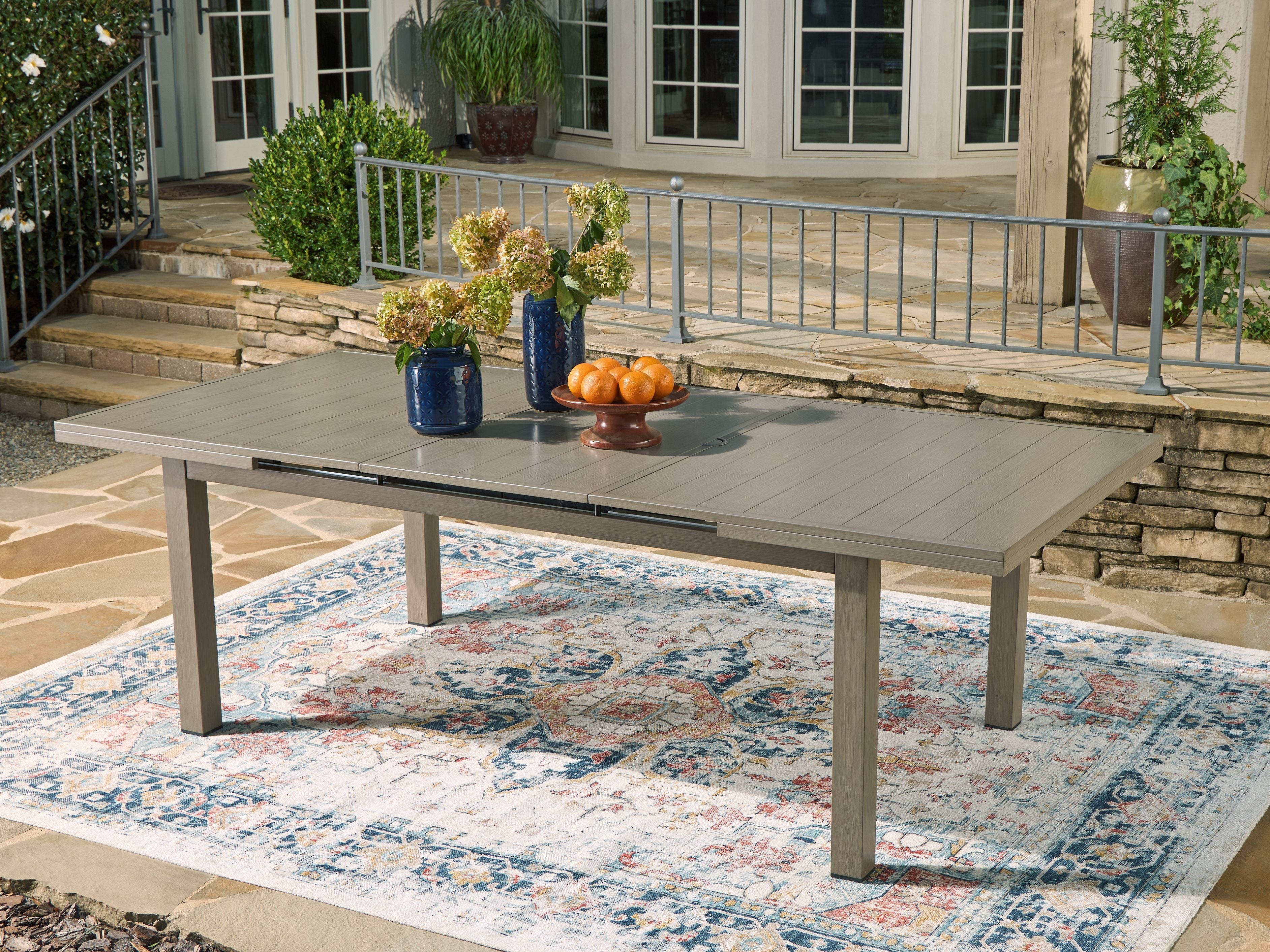 Rectangular outdoor dining table with beige top and four straight legs
