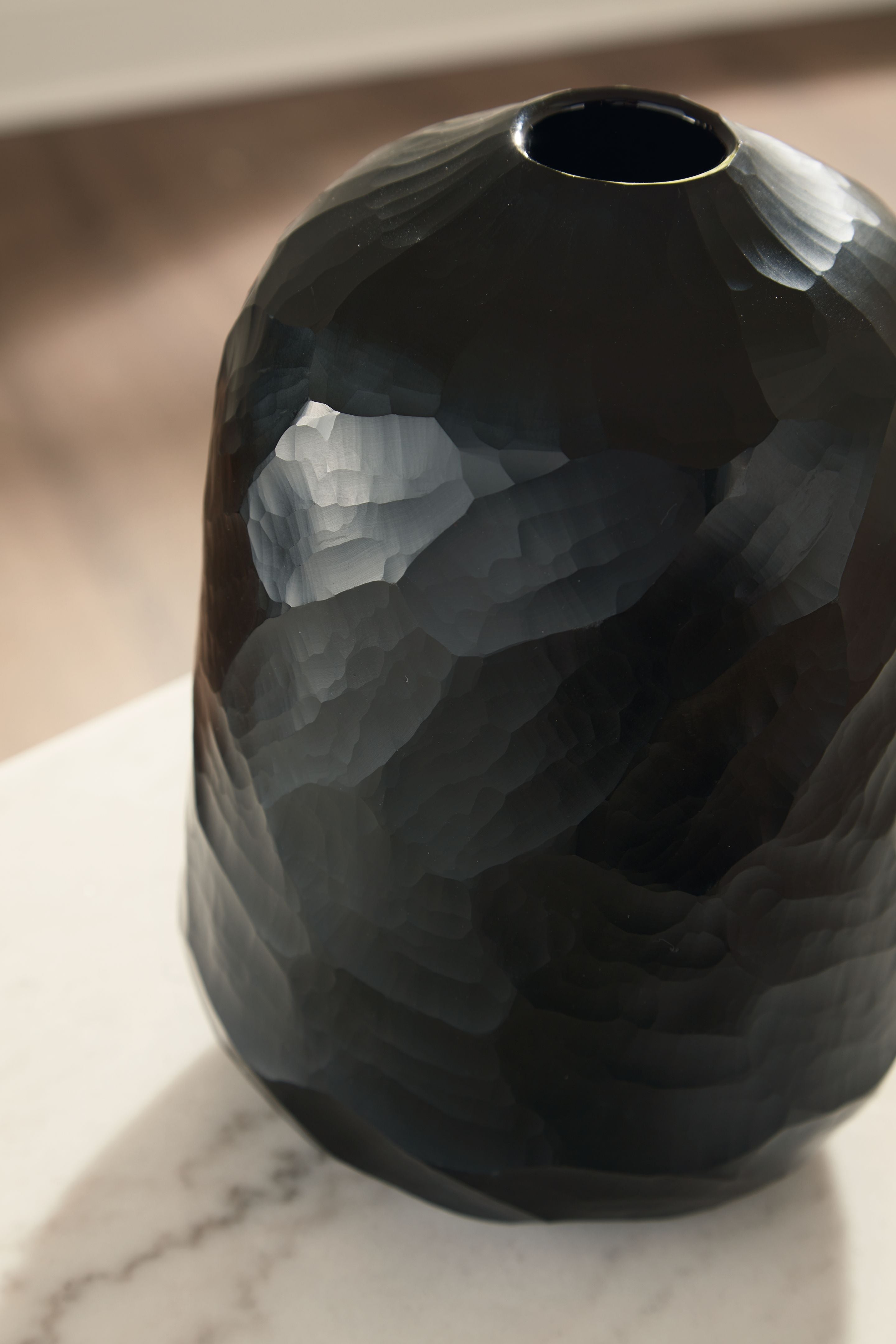 Black faceted vase close view of circular opening and curved body