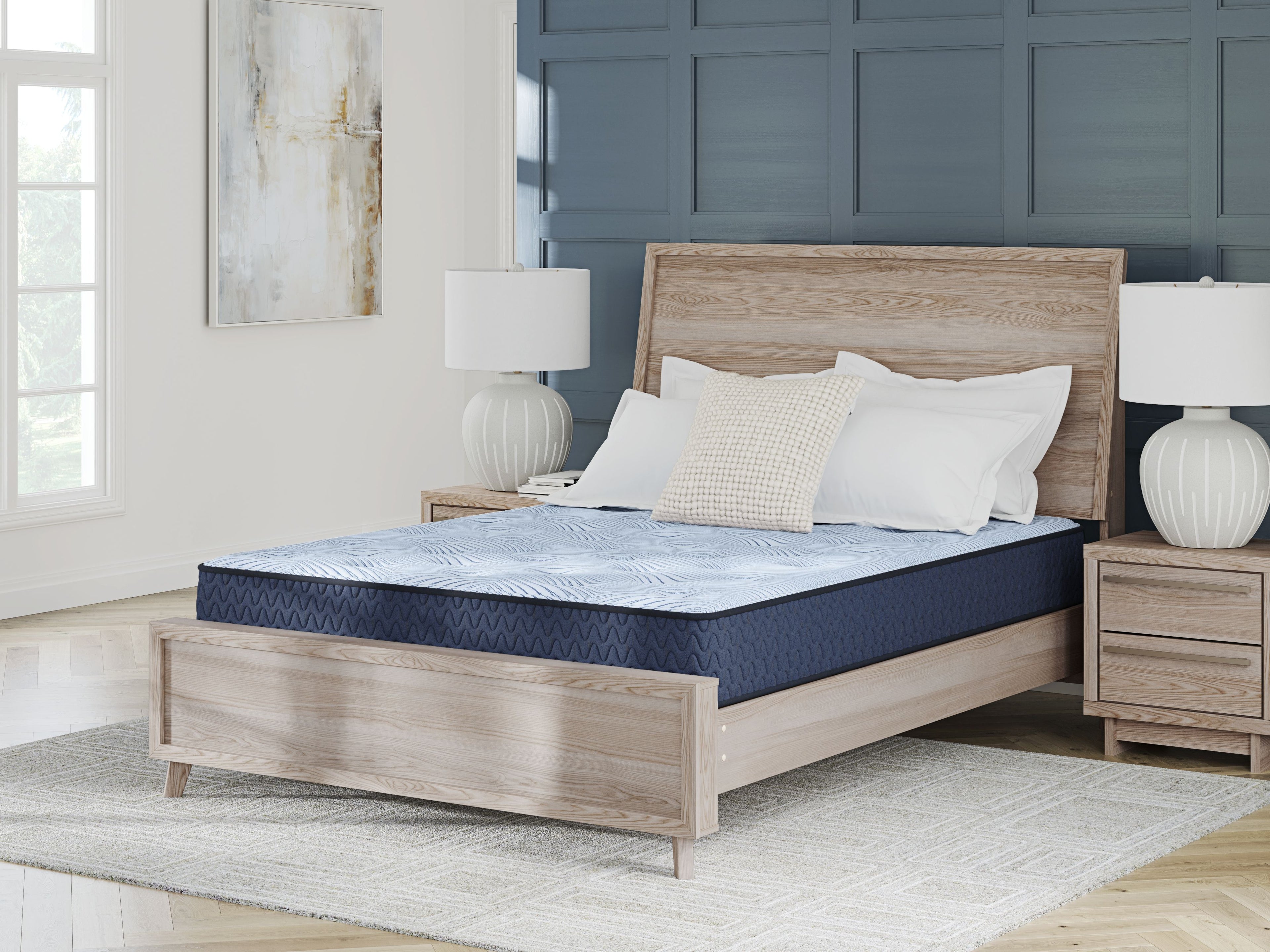 Blue hybrid mattress on a bed frame with white pillows