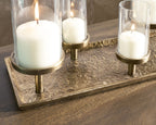 Antique brass candle holder tray with three lit white candles and glass holders