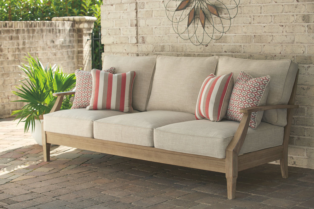 Beige outdoor sofa with wood arms and four throw pillows