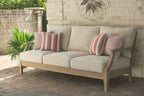 Beige outdoor sofa with wood arms and four throw pillows