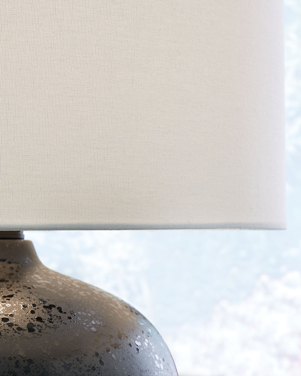 Black speckled ceramic lamp base with visible texture under white drum shade