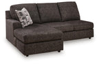 Dark gray sofa chaise with left arm, tufted cushions, and patterned throw pillow