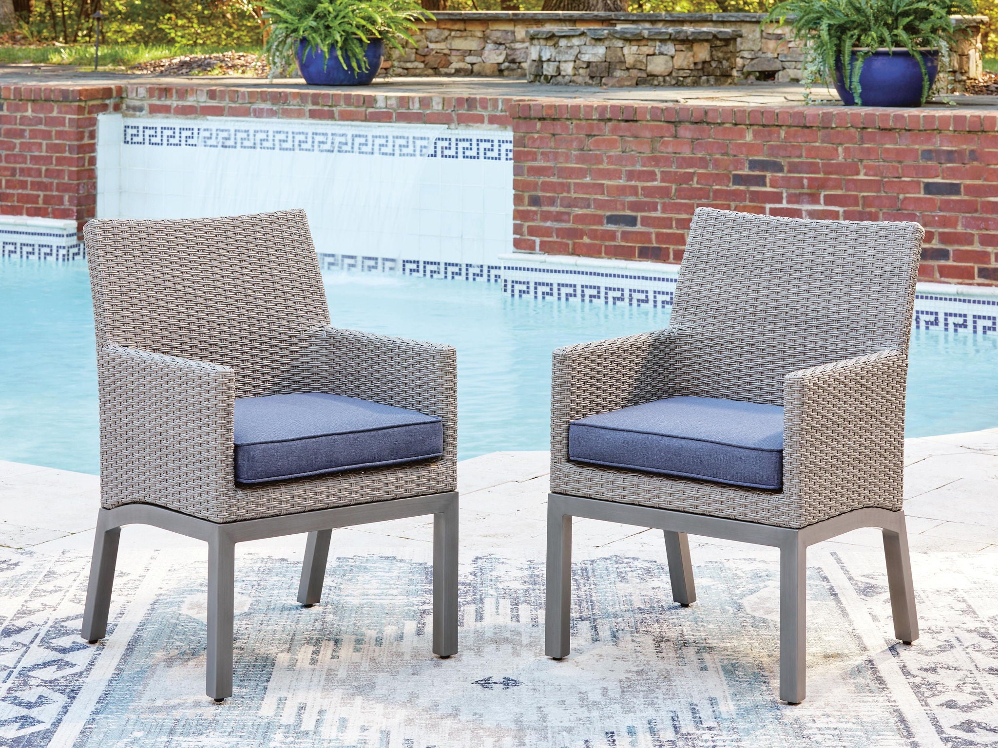 Pair of gray arm chairs with blue-gray seat cushions for outdoor seating.