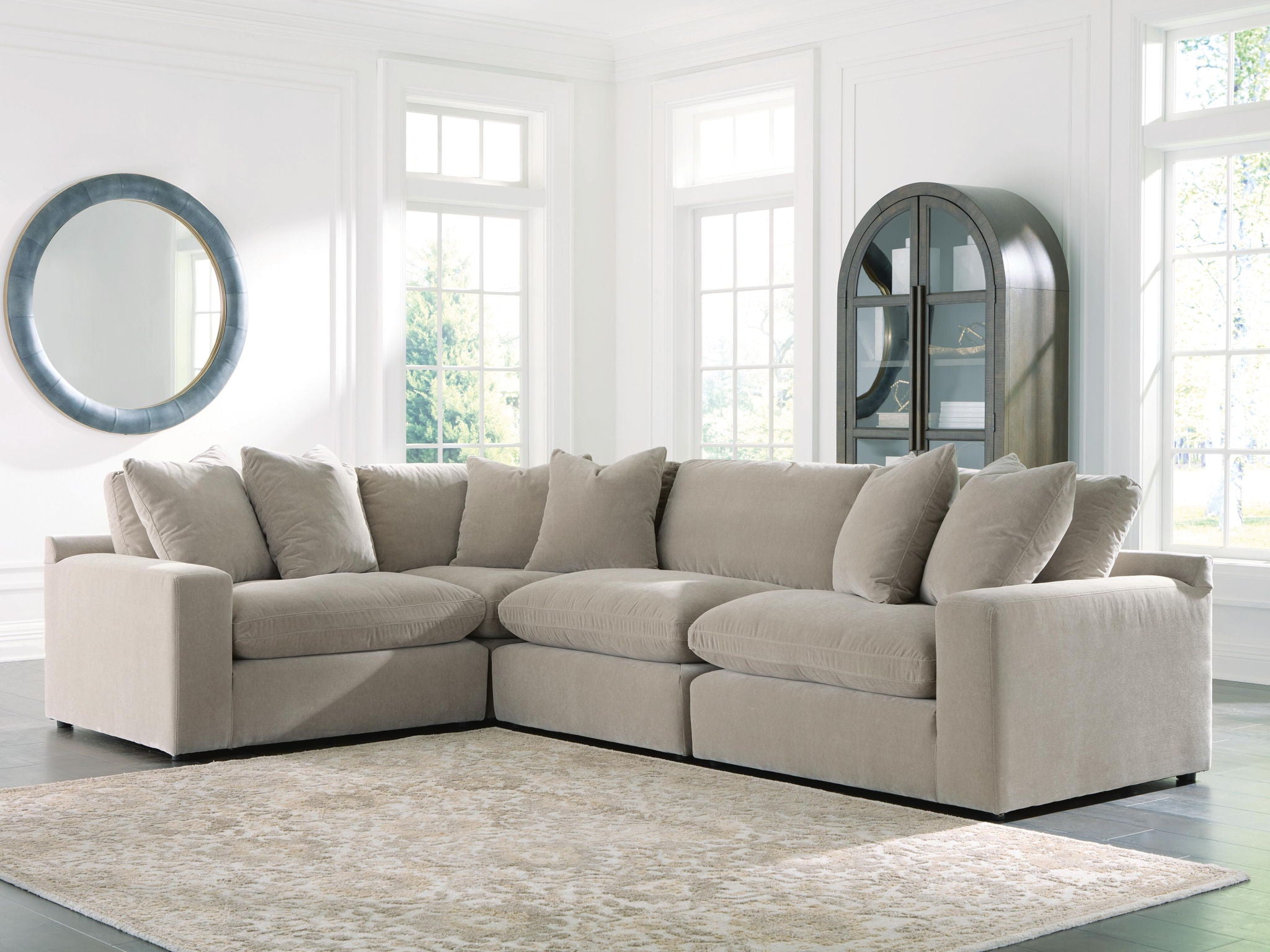 Light gray sectional sofa with padded arms, chaise corner, and plush back cushions and pillows.