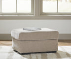 Beige upholstered ottoman with square padded top and black legs